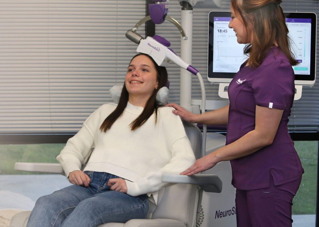 Teenager receiving NeuroStar TMS therapy session guided by a medical professional.